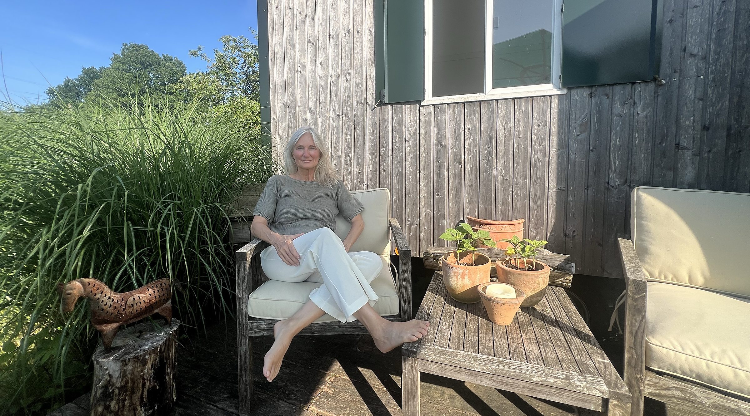 Angelika Allroggen sitzt auf der Terrasse vor dem Gartenhaus, daneben ein zweiter Sessel